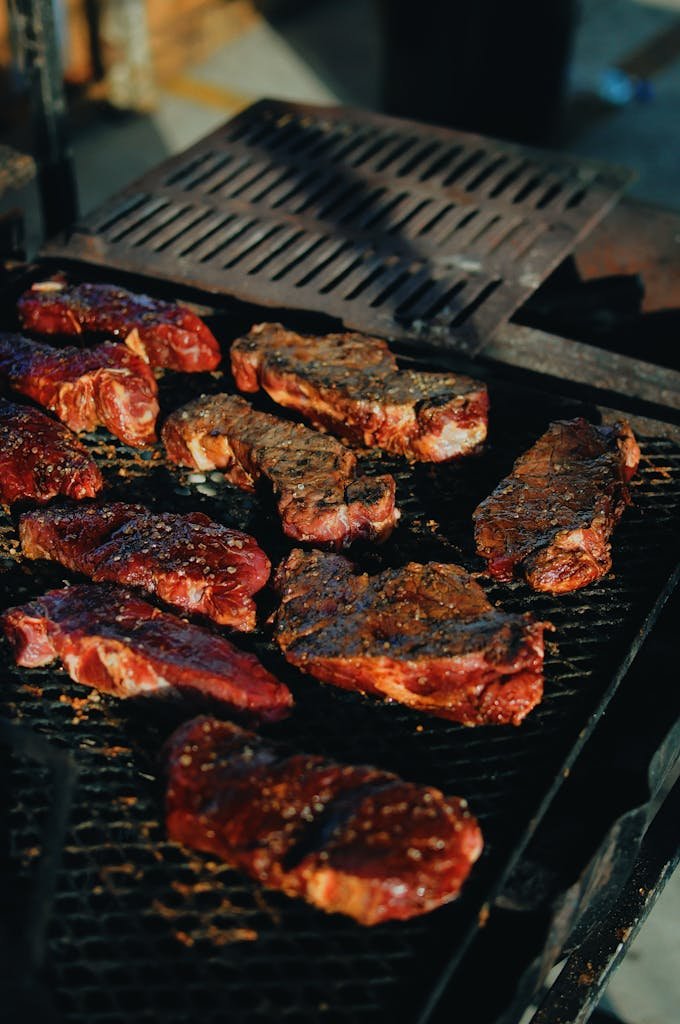 Sizzling steaks on a charcoal grill, perfect for a backyard BBQ.